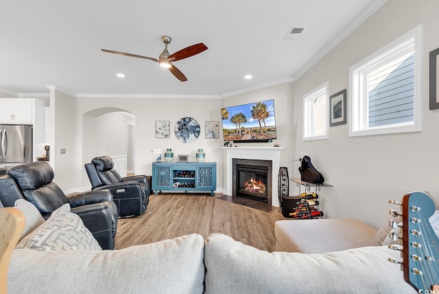 living room with light wood-type flooring, ceiling fan, and crown molding