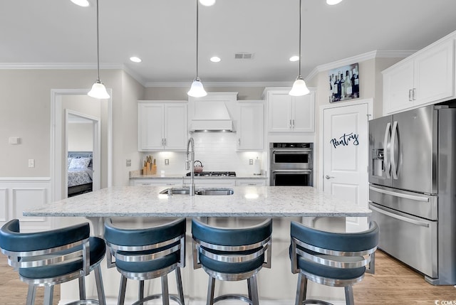 kitchen with white cabinets, appliances with stainless steel finishes, and an island with sink