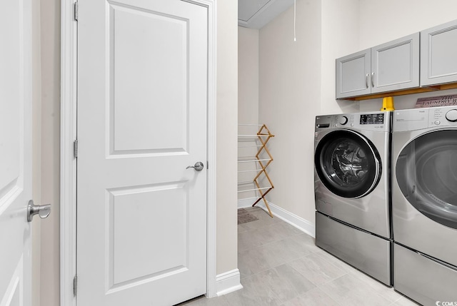 clothes washing area with cabinets, light tile patterned floors, and washing machine and dryer