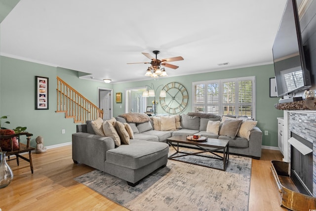 living room with light hardwood / wood-style floors, ceiling fan, and ornamental molding