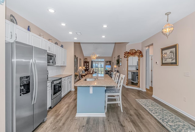 kitchen featuring stainless steel appliances, a kitchen island with sink, white cabinets, and pendant lighting