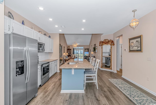 830 San Marco Ct Unit C, Myrtle Beach, SC 29579 - kitchen featuring appliances with stainless steel finishes, white cabinetry, a sink, light wood finished floors, and a kitchen breakfast bar