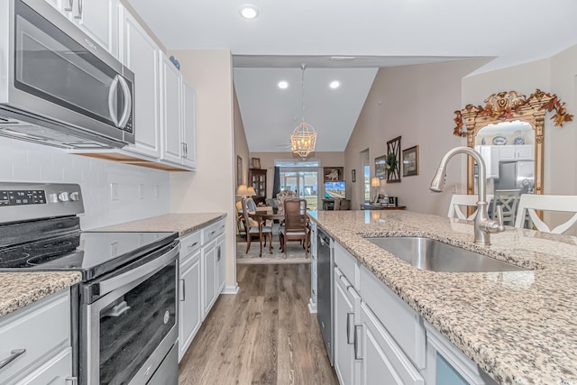 kitchen featuring stainless steel appliances, sink, white cabinetry, decorative light fixtures, and backsplash