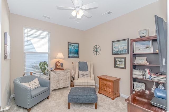 sitting room with ceiling fan, light carpet, and plenty of natural light