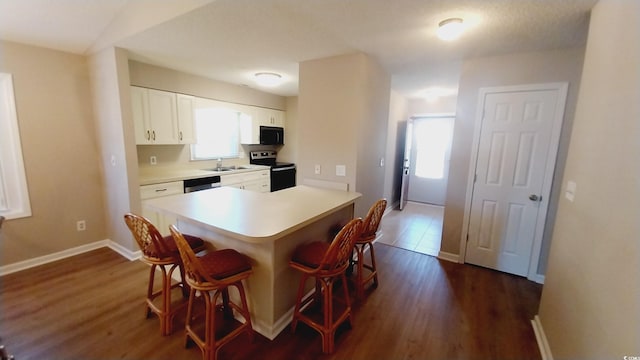 kitchen with a kitchen breakfast bar, stainless steel appliances, sink, dark hardwood / wood-style floors, and white cabinetry