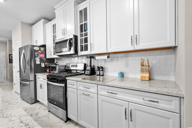 kitchen with backsplash, light stone counters, white cabinets, and stainless steel appliances