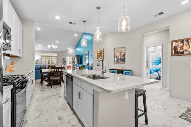 kitchen with appliances with stainless steel finishes, a kitchen island with sink, sink, pendant lighting, and white cabinetry