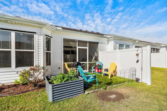 rear view of house featuring a sunroom and a yard