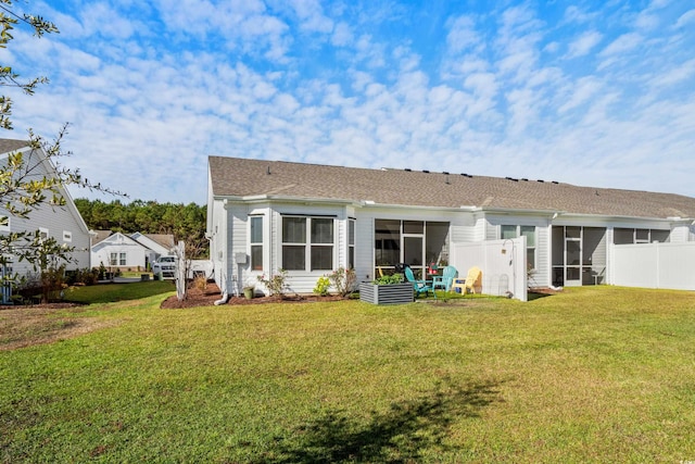 rear view of property featuring a sunroom and a lawn