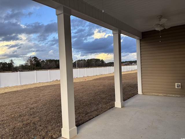 yard at dusk featuring ceiling fan and a patio