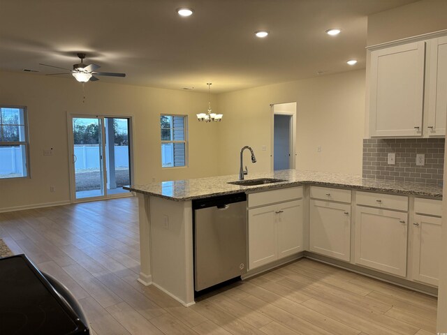 kitchen with dishwasher, sink, white cabinetry, light stone counters, and decorative backsplash