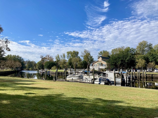 view of community with a boat dock, a lawn, and a water view