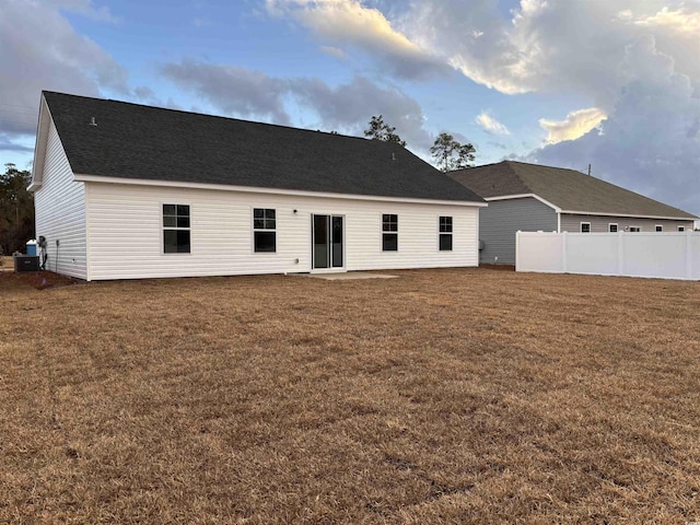 rear view of house featuring cooling unit and a lawn