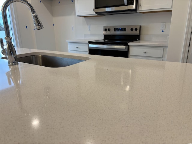 kitchen featuring sink, stainless steel appliances, and white cabinetry