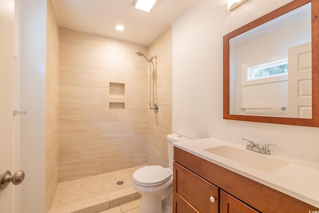 bathroom featuring toilet, vanity, and tiled shower