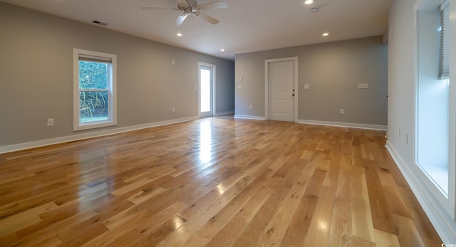 empty room with ceiling fan, a wealth of natural light, and light hardwood / wood-style flooring