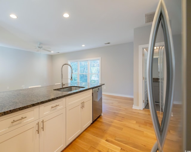 kitchen featuring light hardwood / wood-style flooring, sink, dark stone counters, appliances with stainless steel finishes, and white cabinets