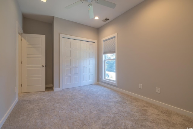 unfurnished bedroom featuring ceiling fan, a closet, and light colored carpet