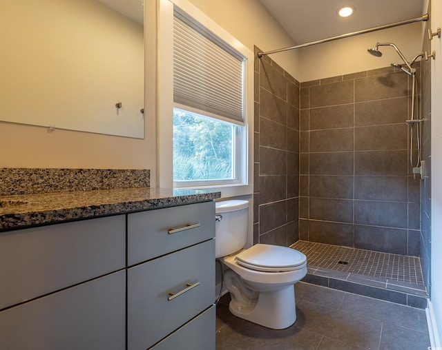 bathroom featuring toilet, vanity, tile patterned flooring, and tiled shower