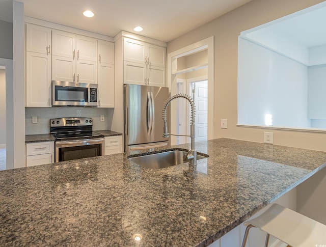 kitchen featuring kitchen peninsula, dark stone countertops, white cabinets, and stainless steel appliances