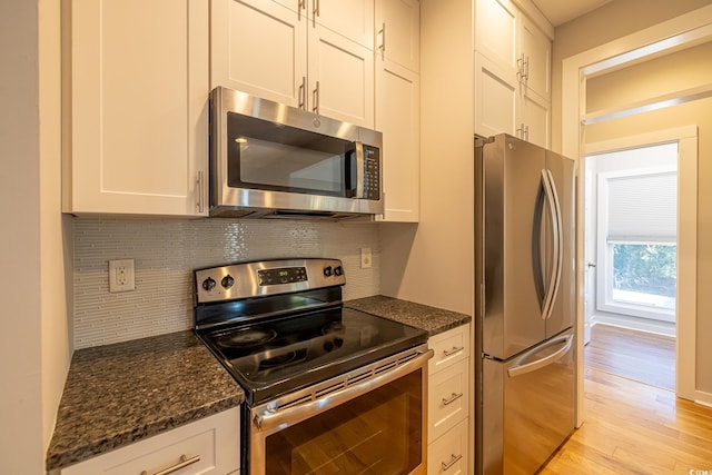 kitchen featuring white cabinetry, tasteful backsplash, dark stone counters, and stainless steel appliances