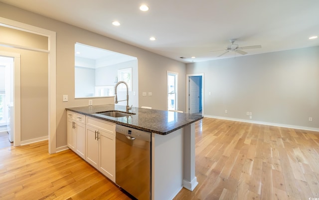 kitchen featuring white cabinets, stainless steel dishwasher, light hardwood / wood-style floors, sink, and dark stone countertops