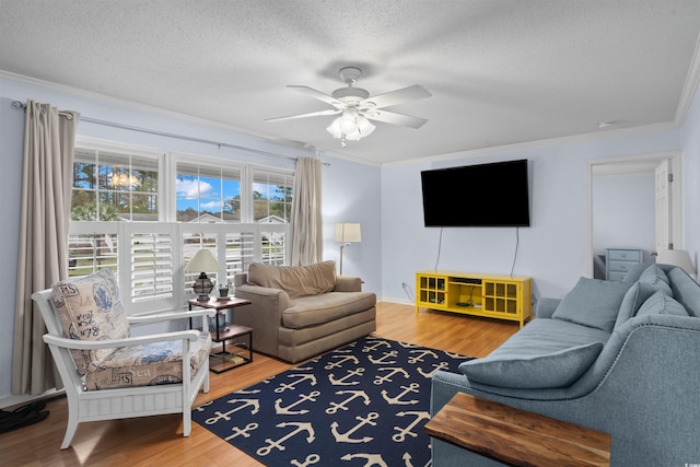 living area with ornamental molding, ceiling fan, a textured ceiling, and wood finished floors