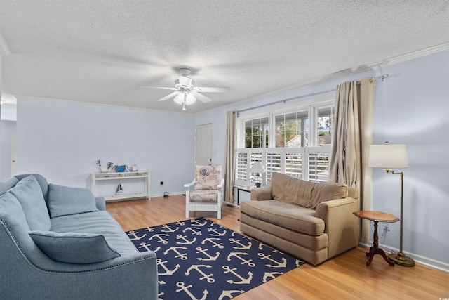 living area with a ceiling fan, a textured ceiling, baseboards, and wood finished floors