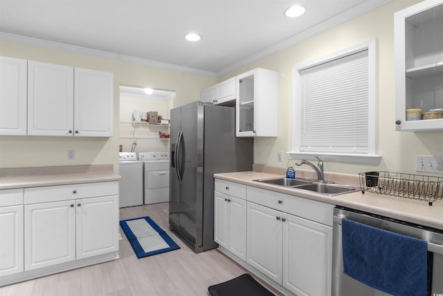 kitchen featuring stainless steel appliances, white cabinets, a sink, and separate washer and dryer