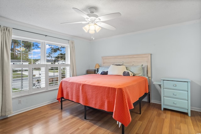 bedroom with a textured ceiling, ornamental molding, light wood-type flooring, and baseboards