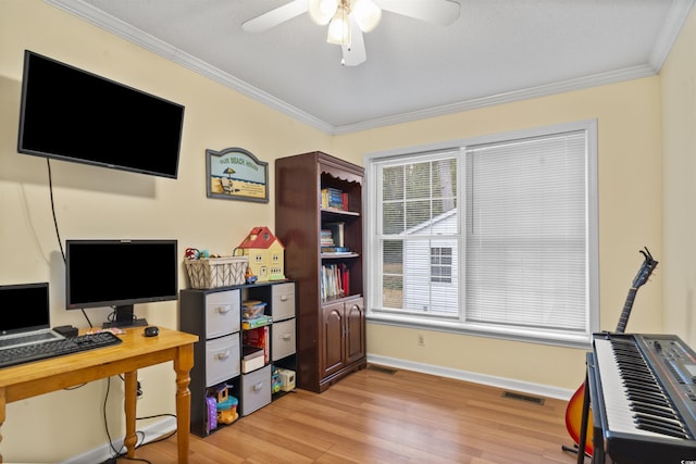 office area featuring light wood finished floors, baseboards, visible vents, ceiling fan, and ornamental molding