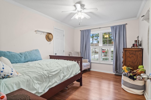 bedroom featuring ceiling fan, baseboards, crown molding, and wood finished floors