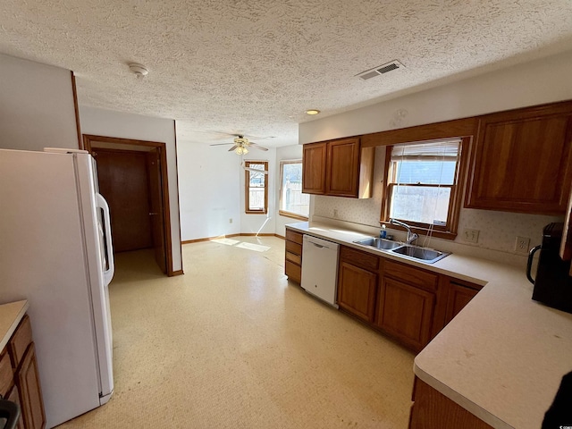 kitchen featuring a textured ceiling, ceiling fan, sink, and white appliances