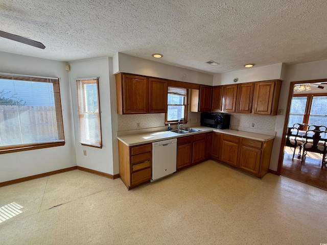 kitchen with ceiling fan, sink, white dishwasher, a textured ceiling, and decorative backsplash