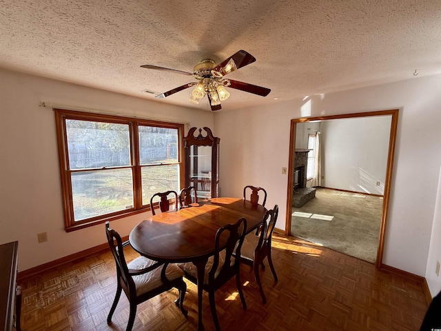 dining area featuring a textured ceiling, dark parquet floors, and ceiling fan