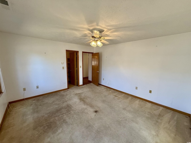 unfurnished bedroom with ceiling fan, light carpet, and a textured ceiling