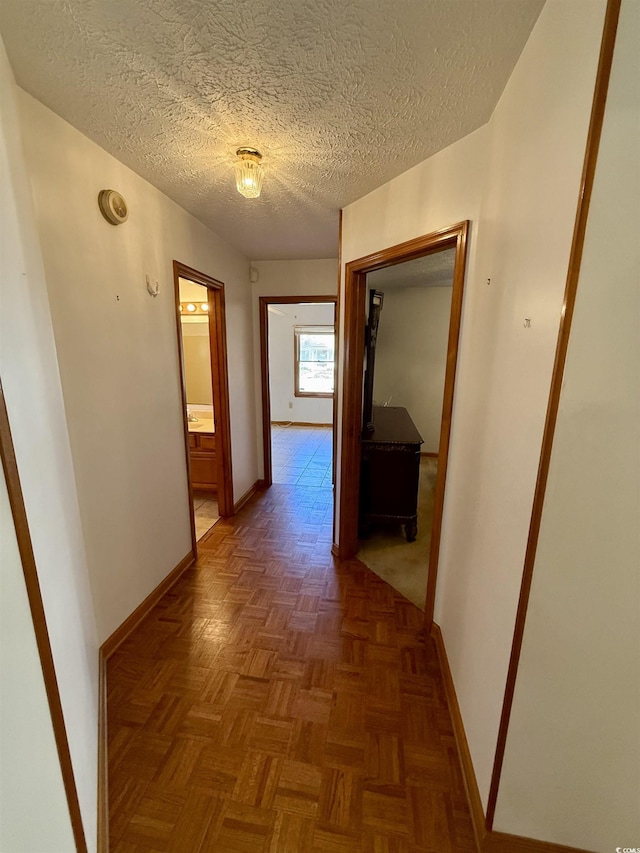 hallway featuring dark parquet floors and a textured ceiling