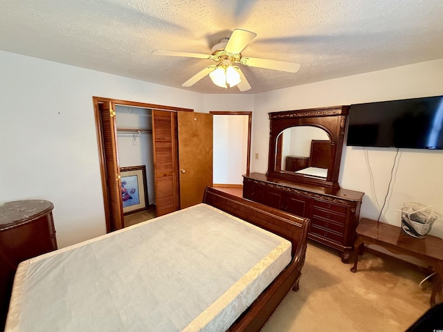 bedroom featuring ceiling fan, a closet, light colored carpet, and a textured ceiling