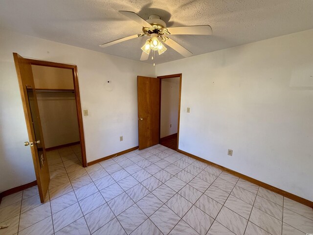 unfurnished bedroom featuring ceiling fan, a closet, a spacious closet, and a textured ceiling