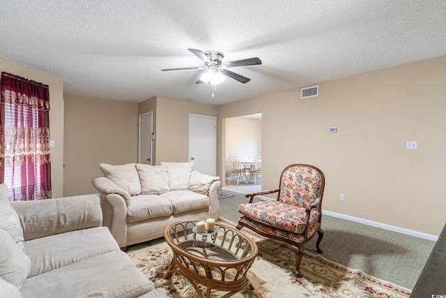 carpeted living room with ceiling fan and a textured ceiling