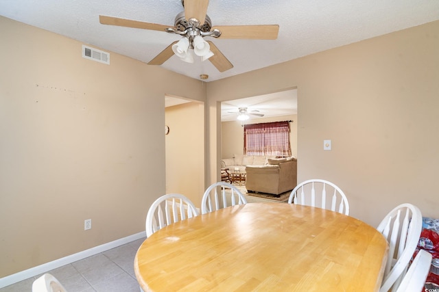 tiled dining area with ceiling fan and a textured ceiling