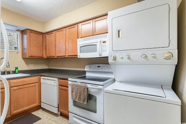 kitchen with stacked washer / drying machine, light tile patterned flooring, white appliances, and a textured ceiling