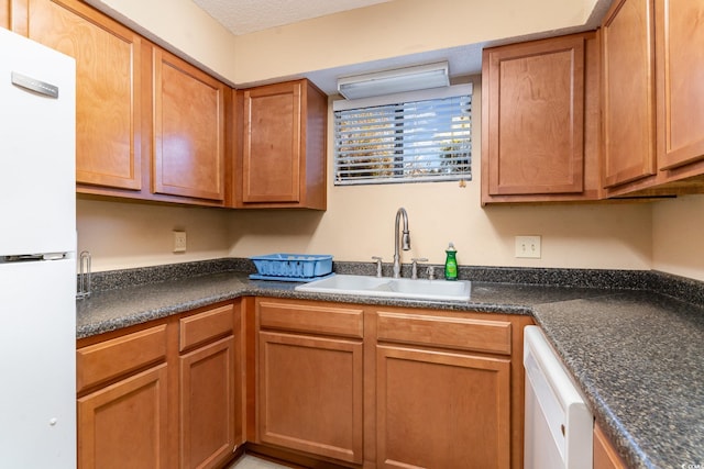 kitchen featuring a textured ceiling, white appliances, and sink