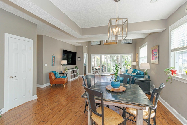 dining area featuring hardwood / wood-style flooring, a notable chandelier, and a textured ceiling