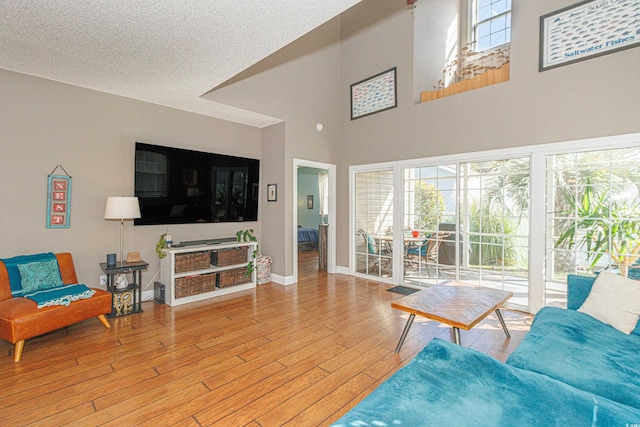 living room featuring a high ceiling, a textured ceiling, and light hardwood / wood-style floors