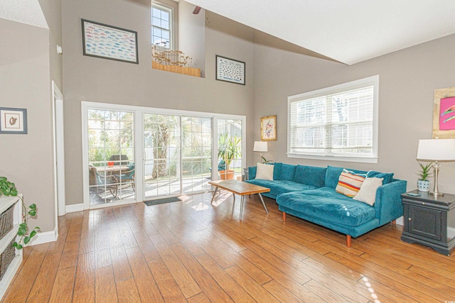 living room with hardwood / wood-style floors, heating unit, a healthy amount of sunlight, and a high ceiling