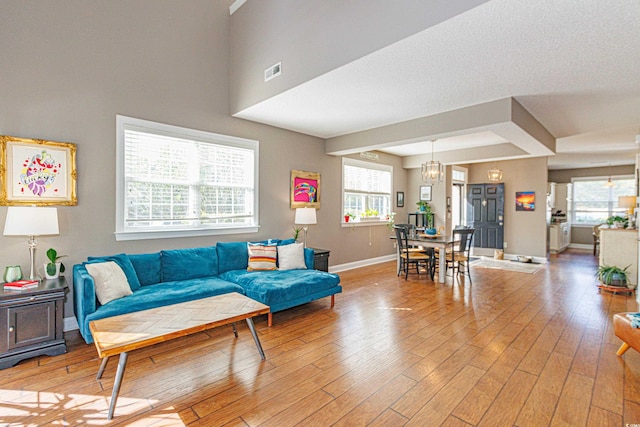 living room featuring a chandelier, light hardwood / wood-style flooring, and a healthy amount of sunlight