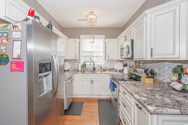 kitchen featuring light wood-type flooring, white cabinetry, sink, and appliances with stainless steel finishes