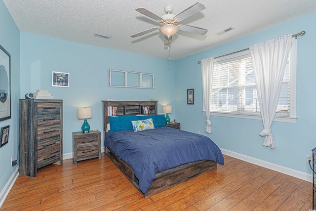 bedroom with ceiling fan, a textured ceiling, and light hardwood / wood-style flooring