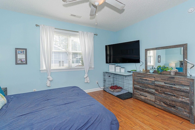 bedroom featuring ceiling fan, light hardwood / wood-style floors, and a textured ceiling